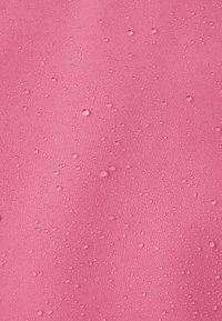 Gocce d'acqua sparse su una superficie rosa strutturata, che evidenziano la resistenza all'acqua e i dettagli del tessuto.