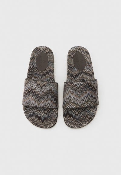 Paire de sandales à enfiler à bout ouvert avec un motif zigzag noir, blanc et marron et une large bride en tissu traversant le pied.