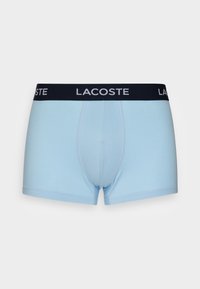Világoskék bokszernadrág fekete elasztikus derékpánttal, rajta fehér "LACOSTE" logóval. Simább anyag, észlelhető szabású, rövid szárhossz.