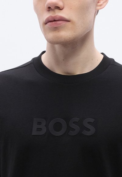 Черна памучна блуза с качулка, със релефно черно лого "BOSS" отпред, рипсена яка и гладка текстура. Прост и модерен дизайн.