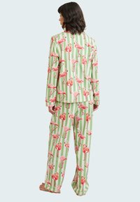 Ensemble de pyjama rayé vert et blanc avec des imprimés de flamants roses, manches longues et pantalons évasés en tissu doux.
