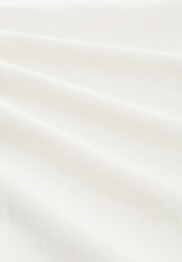 Valkoinen kangas, jossa on sileä tekstuuri, esittelee hienovaraisia taitoksia ja poimuja materiaalin pehmeyden ja kevyen ulkonäön korostamiseksi.