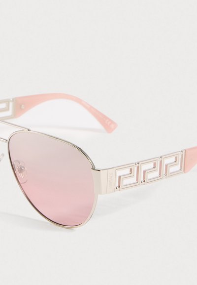 Ochelari de soare stil aviator cu lentile roz și rame argintii, având un model geometric pe sprijină și suporturi pentru urechi roz.