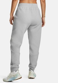 Pantalon de survêtement gris avec une taille élastique et des jambes fuselées. Fabriqué en tissu doux, il présente une texture lisse et des détails de couture subtils.