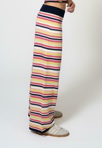 Vara maxi knit yang menampilkan garis horizontal berwarna merah muda, kuning, navy, dan krem. Tekstur lembut, pinggang lebar, dan hem yang kontras.