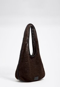 Bolso marrón tejido con una superficie suave y texturizada y bordes negros resistentes; cuenta con un asa curva única para llevar.