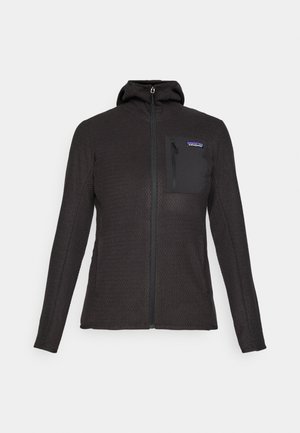 Svart teksturert zip-opp hettegenser med en brystlomme som har glidelås og liten Patagonia-logo-patch på en enkel bakgrunn.
