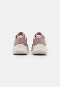 Scarpe da atletica rosa in rete con un retro testurizzato, suola bianca imbottita e piccolo logo grigio vicino al tallone. Design a basso profilo con colletto imbottito.