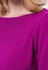 Magenta neulepullovaihtoehto, jossa on leveä kaula-aukko, pehmeä tekstuuri ja hieman löysä istuvuus, esittelee sileää kangasta ja siistejä sauman yksityiskohtia.