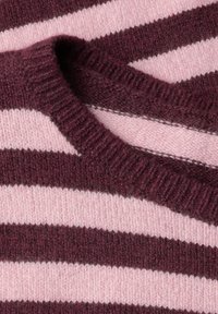Gros plan sur un tissu tricoté à rayures horizontales roses et violet foncé avec un col côtelé plié.