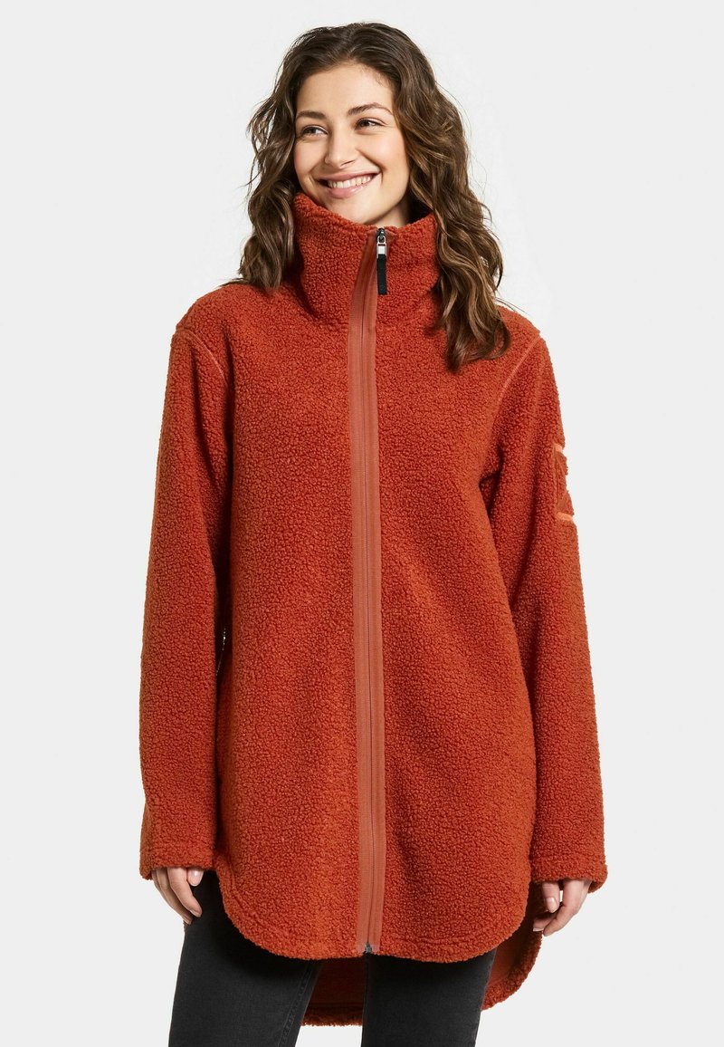 Rustrød fleecejakke med høj krave, fuld frontlynlås og lange ærmer. Har et tekstureret, blødt materiale med en buet kant.