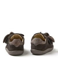 Zapatos de ante gris con un respaldo texturizado y un acento brillante. Presentan un detalle de lazo en los laterales. Suelas flexibles para mayor comodidad.