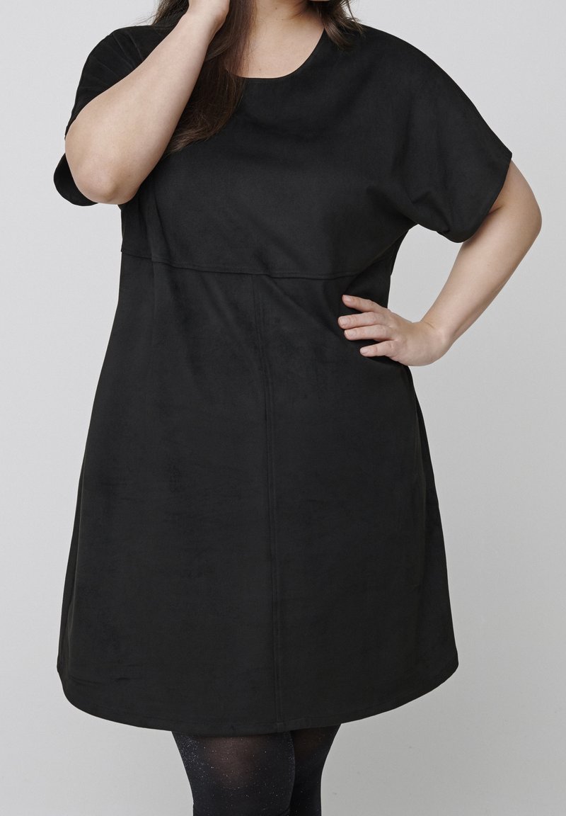 Robe noire à manches courtes avec un col rond, fabriquée dans un tissu doux et lisse. Présente un corsage ajusté et une jupe évasée. Design de couture simple.