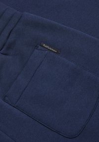 Marineblauwe sweatshirt met een gladde textuur, voorzien van een zak aan de voorkant en een klein Peak Performance-label in de stof genaaid.