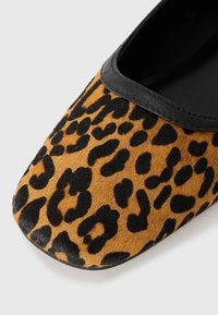 Ballet flat con stampa leopardata e una morbida texture in pelliccia, caratterizzato da un bordo nero attorno all'apertura e una punta arrotondata.