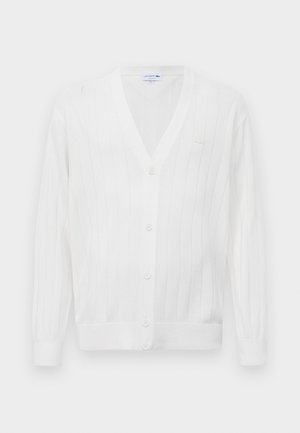 White knitted cardigan with a v-neck, ribbed texture, five buttons down the front, and a small embroidered logo on the left chest.