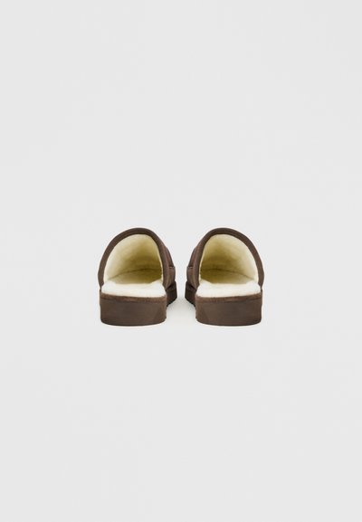 Hnědé nazouvací pantofle s měkkou krémovou podšívkou a plochou podrážkou. Design je jednoduchý, bez dalších ozdob.