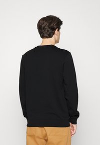 Sudadera negra de mezcla de algodón, con cuello redondo, puños y dobladillo acanalados. La vista trasera muestra un diseño liso y simple.