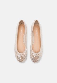 Ballerines beige avec un revêtement de sequins, bout rond, bord élastiqué et nœud décoratif. Doublure intérieure et semelle lisse.