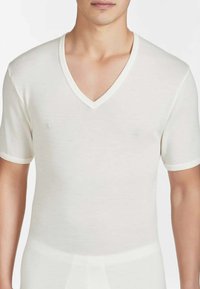 T-shirt bianca con scollo a V e maniche corte, realizzata in un tessuto liscio e leggero con bordatura bianca a contrasto intorno allo scollo e alle maniche.