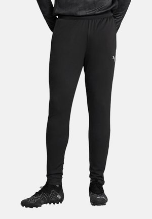 Zwarte sportbroek met een taps toelopende pasvorm, elastische tailleband en subtiele branding. Gecombineerd met zwarte voetbalschoenen met een gestructureerd ontwerp.