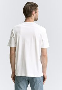 Hvid bomulds T-shirt med korte ærmer, rund hals og en afslappet pasform. Ingen synlige mønstre eller hardware. Enkel, glat tekstur.