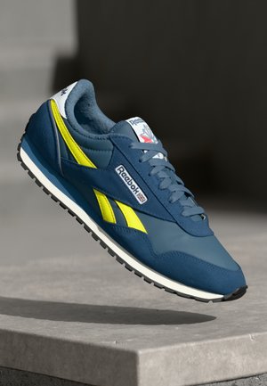 Reebok sneakers med en mørkeblå overdel med gule detaljer, glat læder og ruskindsmaterialer samt en struktureret sort gummisål.