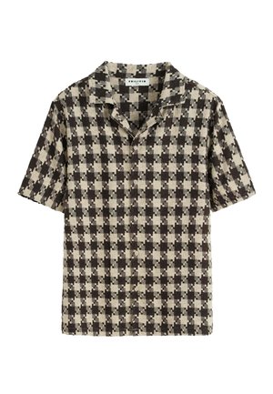 Chemise à manches courtes avec un motif à carreaux noir et beige, dotée d'un col et de boutons à l'avant, fabriquée en tissu texturé.