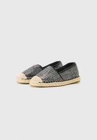 Svarte og hvite vevde lerrets espadrillosko med såle i jute, svarte elastiske sideelementer, avrundet tå og flat hæl.