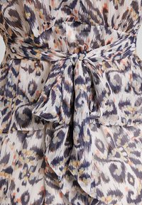 Robe en tissu plissé aux couleurs claires avec un motif abstrait bleu, violet et pêche. Dotée d'un détail à la taille nouée pour une silhouette définie.