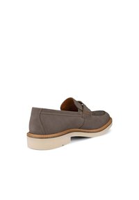 Braune Wildleder-Slipper mit genähten Details, einer beige Sohle und einem niedrigen Absatz, schräg positioniert, um die innere Seite und die Rückseite zu zeigen.