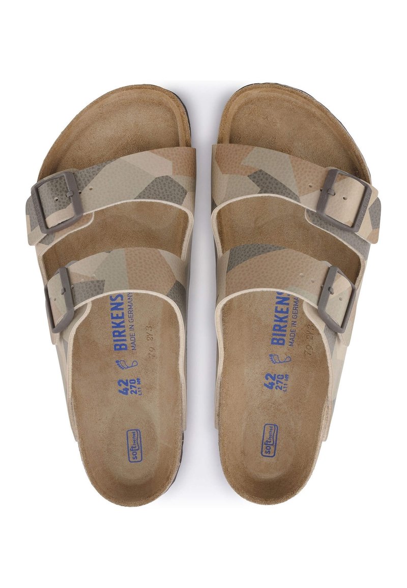 Un paio di sandali Birkenstock beige e marrone con motivo camouflage, dotati di due cinturini regolabili con fibbie e plantari in pelle scamosciata.