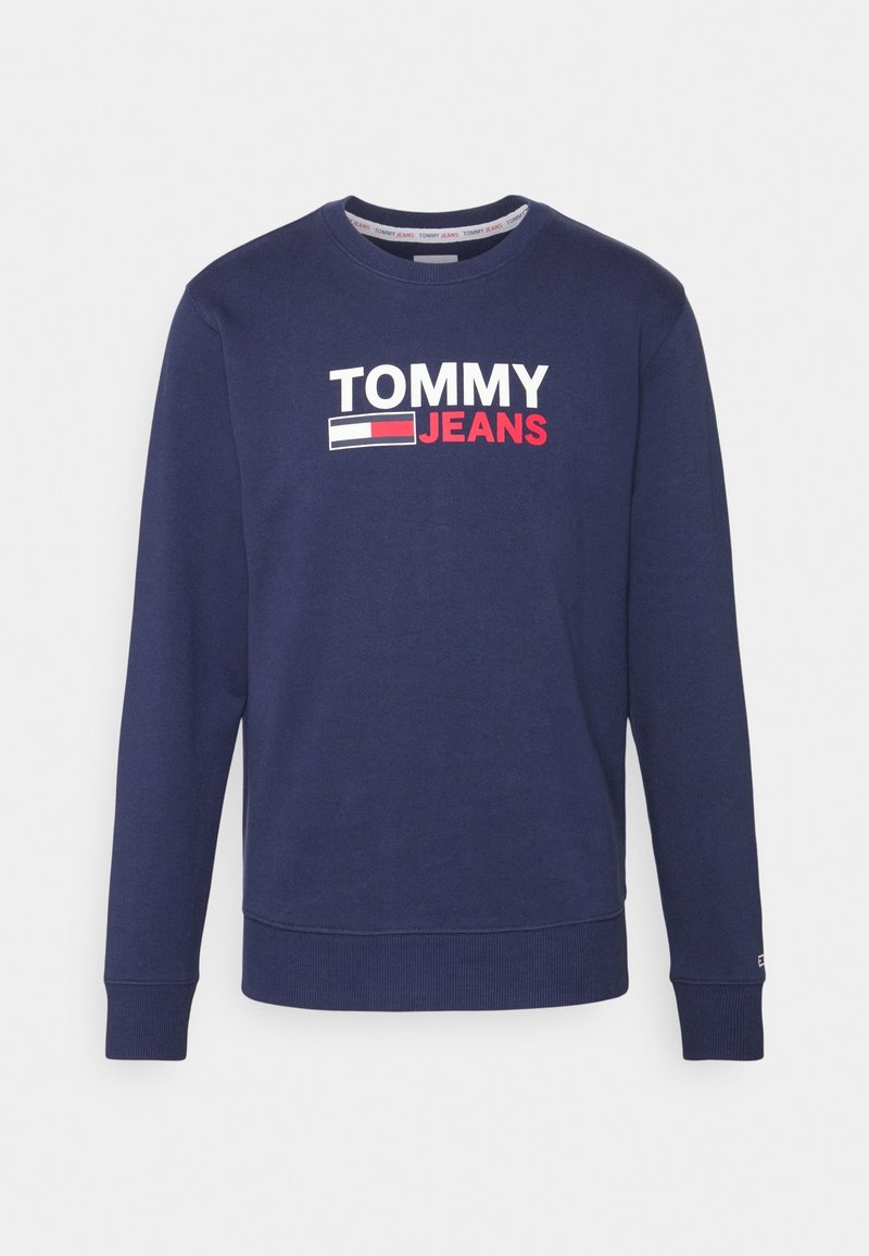 Mörkblå crewneck sweatshirt med långa ärmar, med vit och röd "TOMMY JEANS"-logotyp och flagg emblemet på bröstet.
