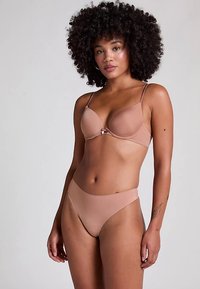 Beha- en ondergoedset in een nude tint. De beha heeft gladde cups en verstelbare bandjes. Het taillehoogslippje heeft een naadloos ontwerp.