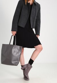 Grå ulljacka, svart plisserad klänning, grå läderhandväska och taupe mockastövletter med dragkedjedetalj samt svarta strumpor.