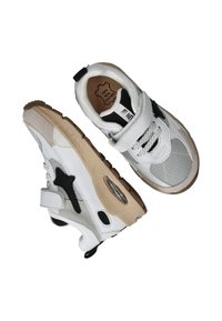 Baskets blanches en matériaux mesh et cuir, avec un logo en forme d'étoile noire, une sangle ajustable et une semelle beige avec une unité d'air visible.