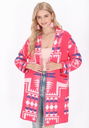 Flauschige pinke Strickjacke mit geometrischen Mustern in Weiß und Blau, offenes Design, lange Ärmel und seitliche Taschen. Lässiger und gemütlicher Schnitt.
