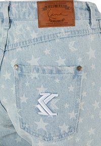 Heled sinised denim lühikesed püksid, millel on valged tähtede mustrid, nahast logo silt ja valged tikandid tagaseljal taskul.