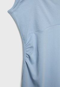 Haut sans manches bleu clair avec couture latérale froncée et texture en maille fine côtelée.