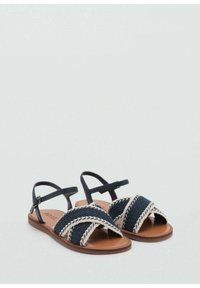 Sandali intrecciati blu navy con fasce incrociate, dettagli intrecciati beige, suola marrone e cinturino alla caviglia. Design flat, stile open toe.
