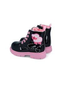 Botas de tobillo de charol negro con detalles en rosa, forro de felpa y un aplique de oveja en el lateral, que cuentan con una suela de goma rosa.