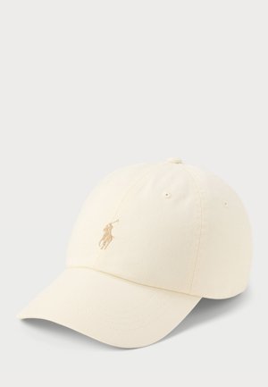 Casquette de baseball de couleur crème avec visière incurvée et logo brodé d’un joueur de polo sur le panneau avant sur fond clair.