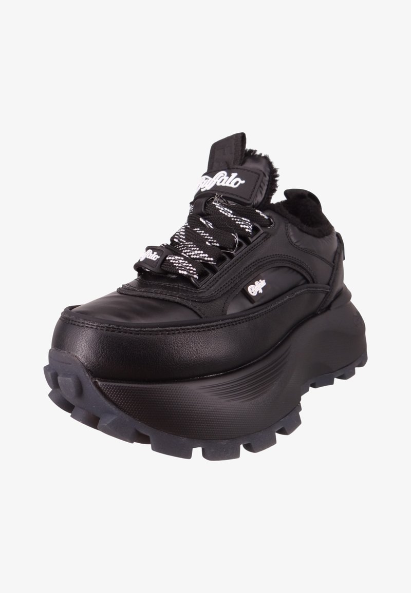 Zapatilla negra con suela gruesa, parte superior de cuero, detalles texturizados y cordones de patrón en blanco y negro. Cuenta con un collar acolchado y un detalle de logo.