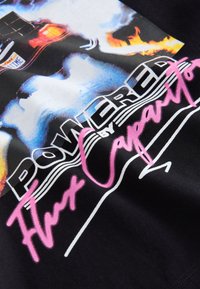 Tricou negru cu un grafic colorat al unei mașini cu flăcări, textul "Alimentat de Capacitorul de Flux" în alb și roz. Țesătură moale de bumbac.