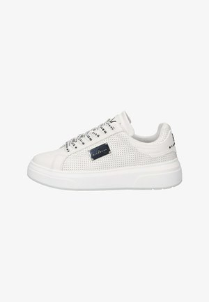 Sneaker bianca bassa con lati traforati, lacci brandizzati bianchi e neri, piastra con logo in metallo e suola spessa bianca.