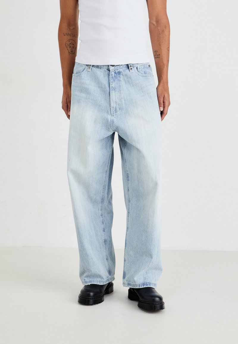 Lys blå denimbukser med løs passform, rett benform og falmet tekstur, kombinert med svarte kraftige støvler.