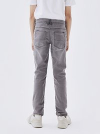 Jeans de mezclilla gris con un ajuste slim, que cuentan con bolsillos traseros, un sutil desteñido y una cinturilla con un detalle de bucle central.