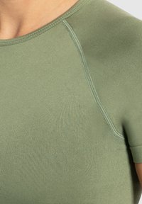 Lichtgroen, sportshirt met korte mouwen, gemaakt van een soepele en rekbare stof met contrasterende naaddetails. Ronde halslijn, getailleerd ontwerp.