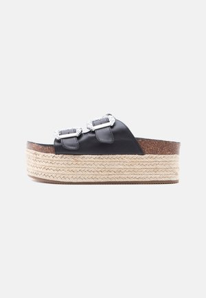 Sandalia plataforma negra con dos hebillas plateadas ajustables y suela de yute trenzado sobre un fondo blanco.