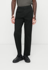 Black elastic waist trousers made of lightweight fabric, featuring a straight cut, subtle sheen, and a button closure at the front.